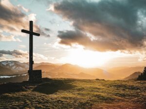 a cross sitting on top of a lush green hillside