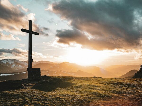 a cross sitting on top of a lush green hillside