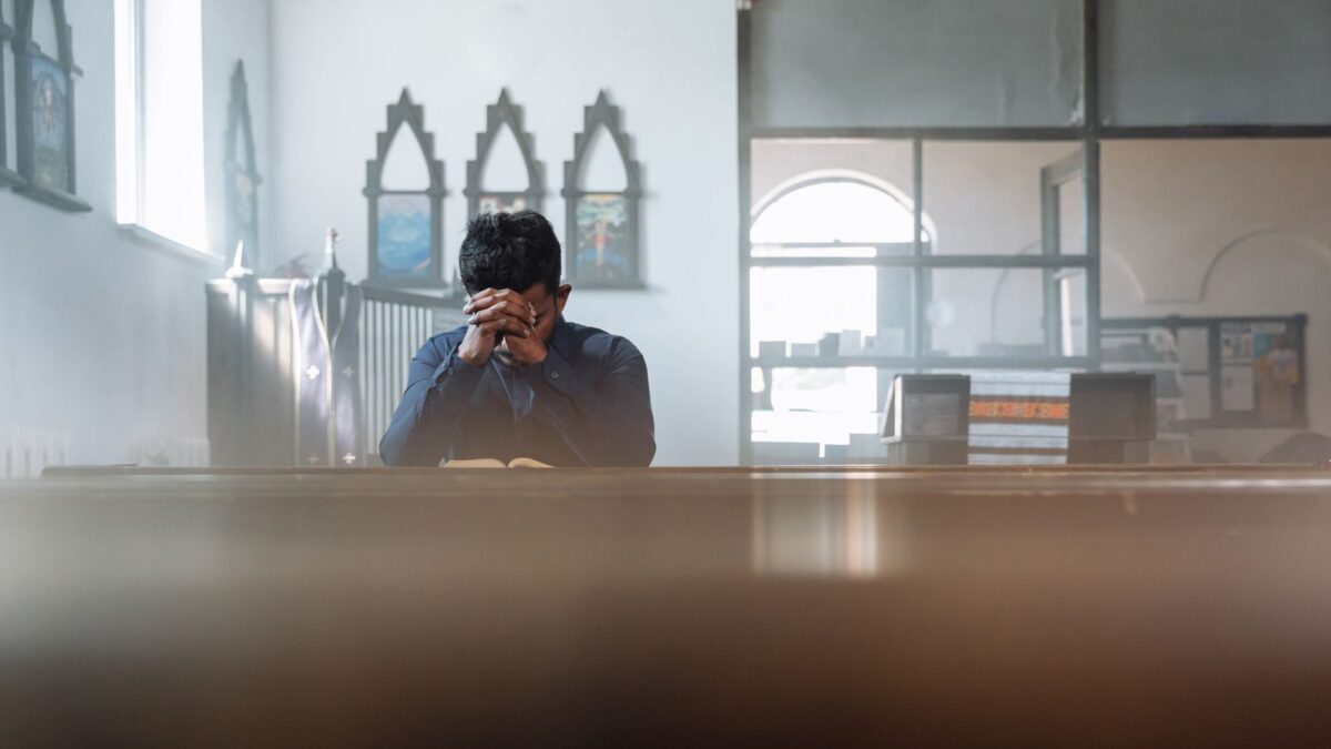 A man in prayer in a sunlit room, reflecting spirituality and peace.