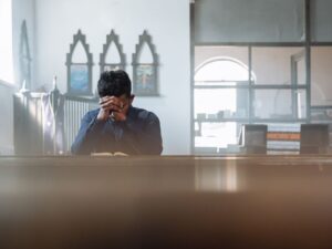 A man in prayer in a sunlit room, reflecting spirituality and peace.