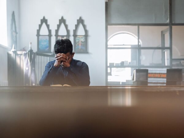 A man in prayer in a sunlit room, reflecting spirituality and peace.