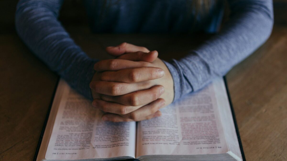 man holding his hands on open book