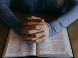 man holding his hands on open book